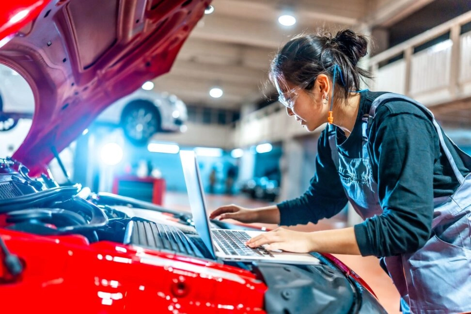 A female quality engineeer checking a laptop on a car