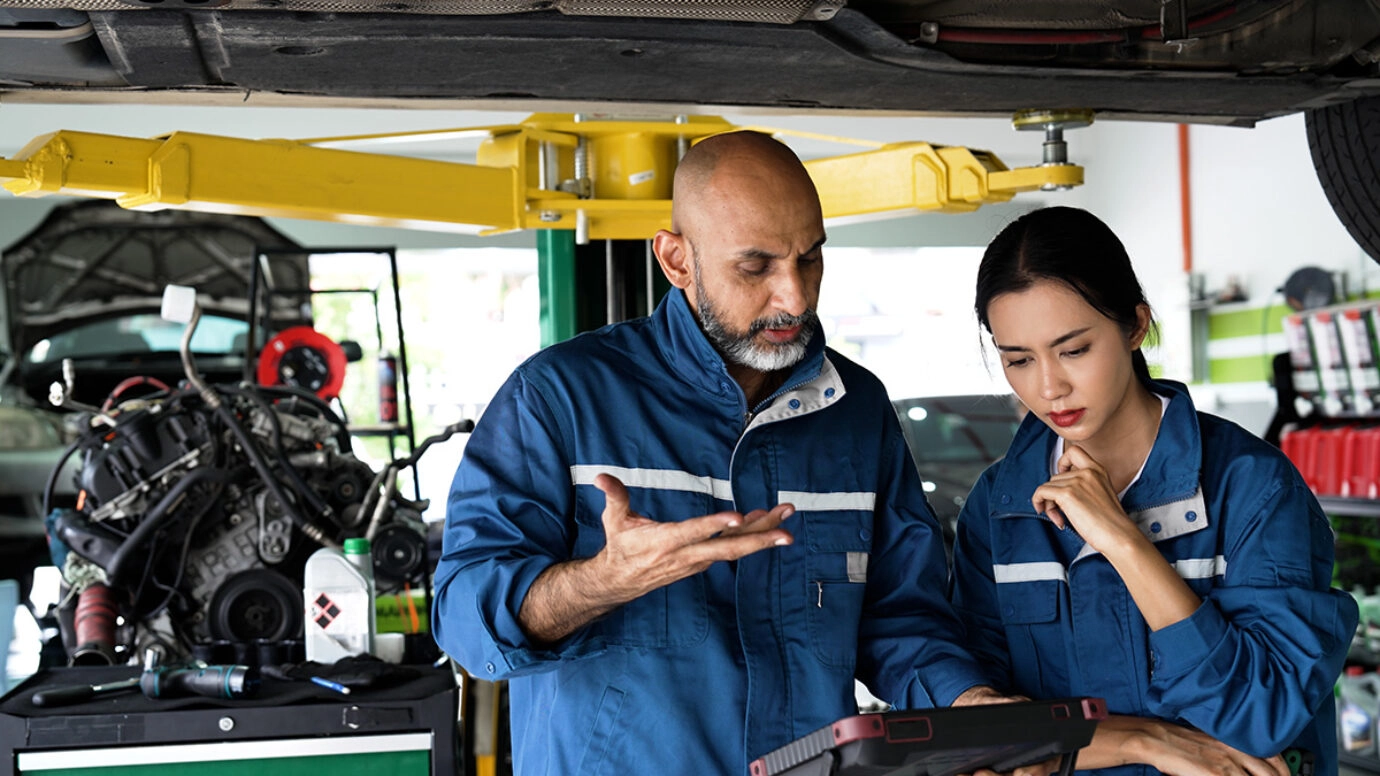 Women and men looking at a laptop on a factory