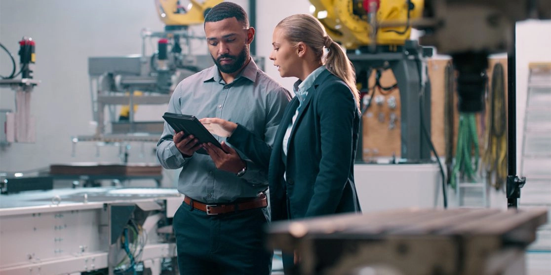 A men and a women are checking a document in a manufacturing facility