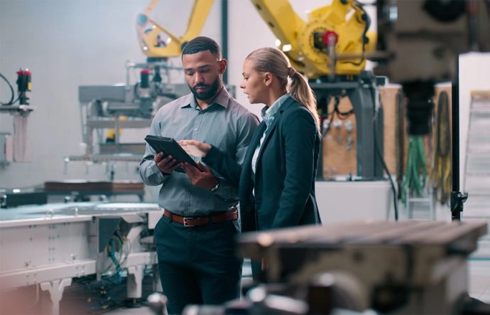 A men and a women are checking a document in a manufacturing facility